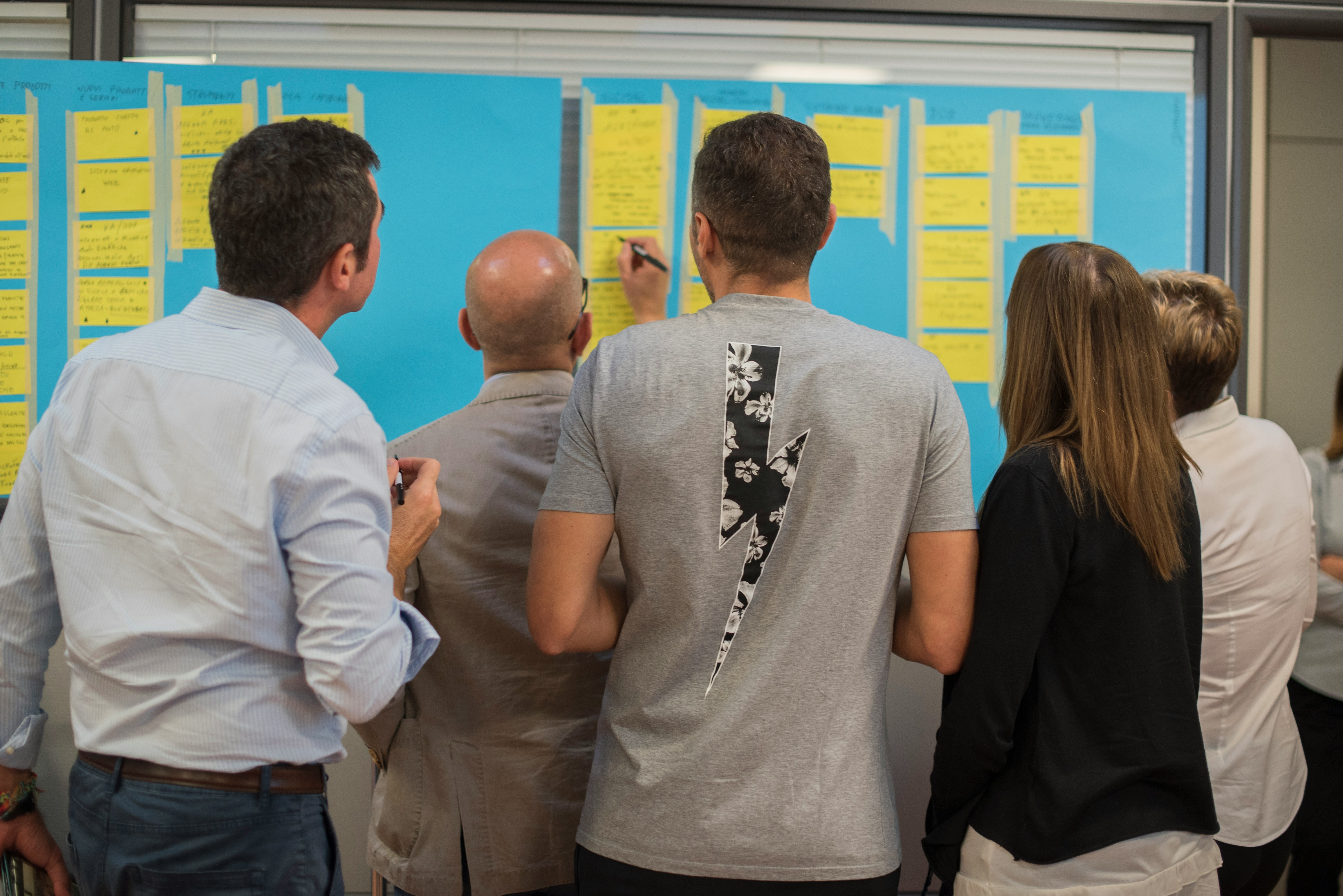 A group of SSE colleagues round a board adding sticky notes and ideas to a board