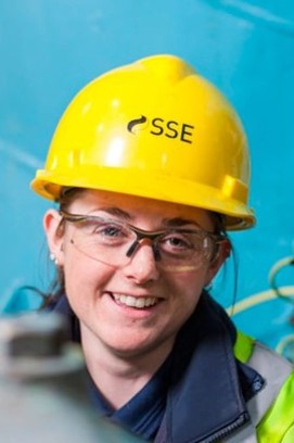 An up-close image of a female engineer’s head wearing a SSE branded hard hat and safety goggles whilst smiling