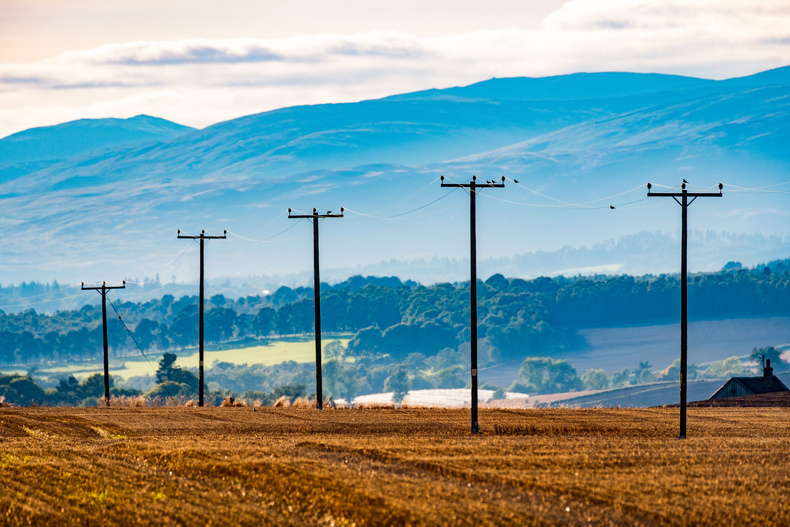 Power Lines in a field with mountains in the background