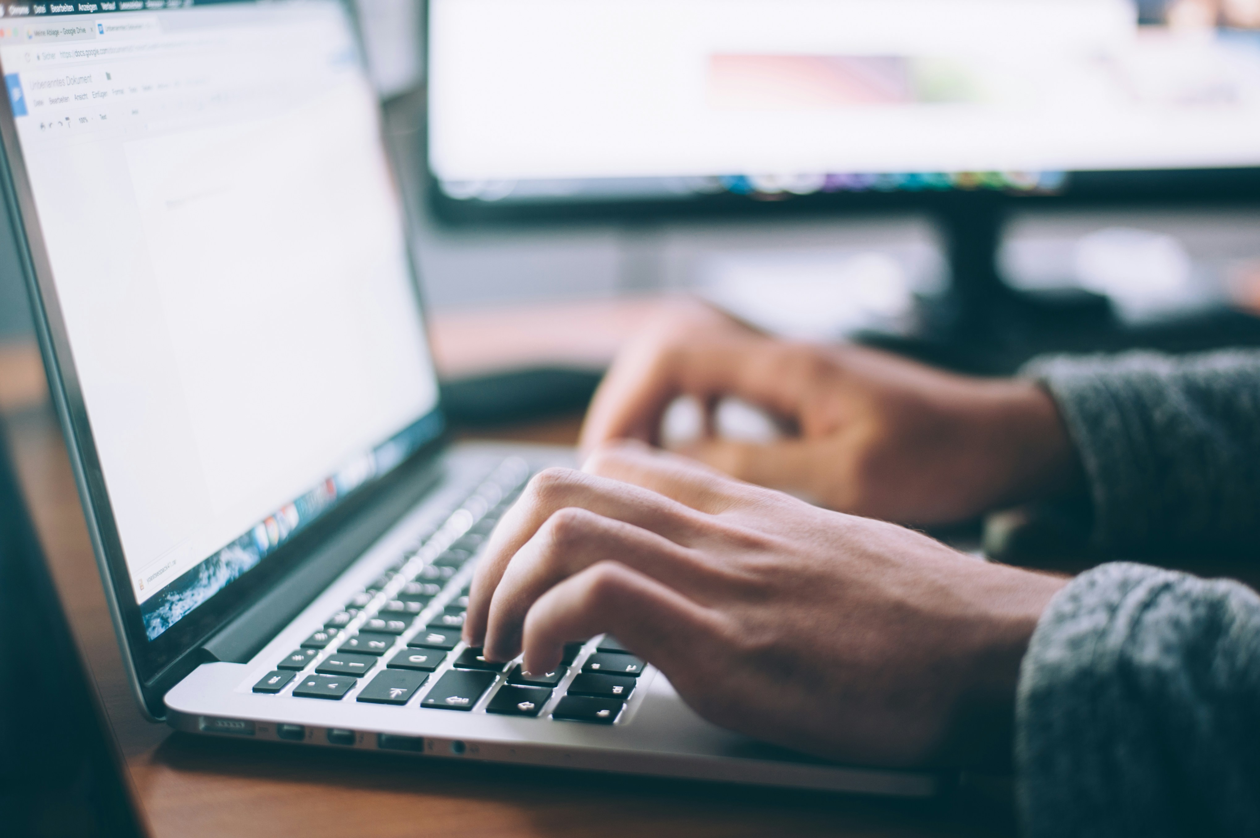 A pair of hands typing on a laptop